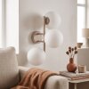 Modern globe wall light Gastor with three white glass shades for the couch